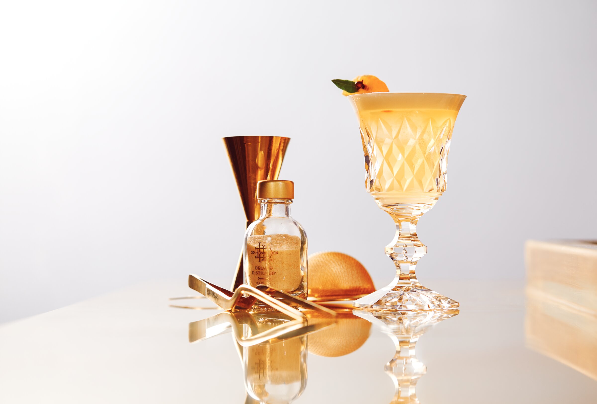 Cocktail in a crystal glass with gold bar tools, editorial still life