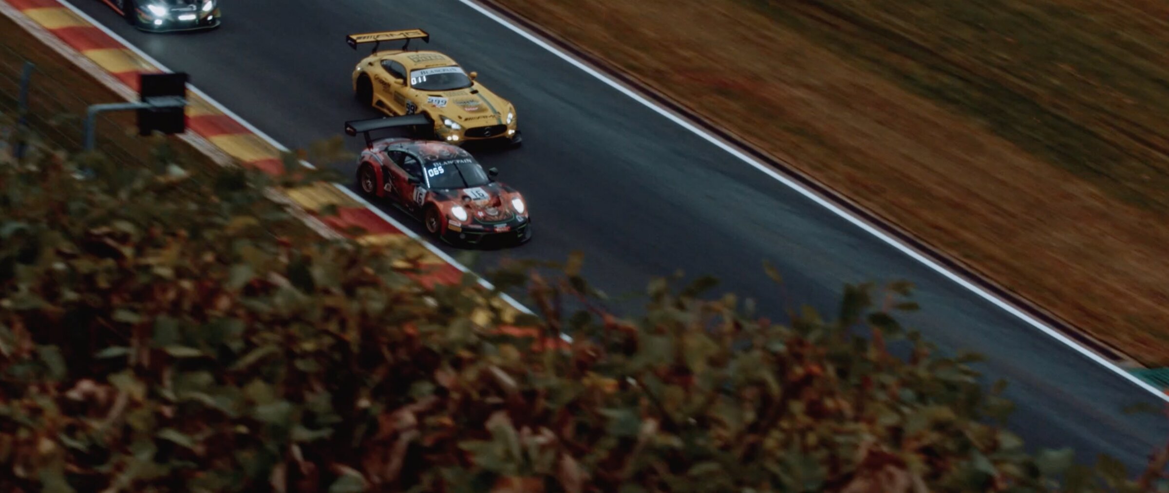 Elevated view of GT cars cornering through Eau Rouge