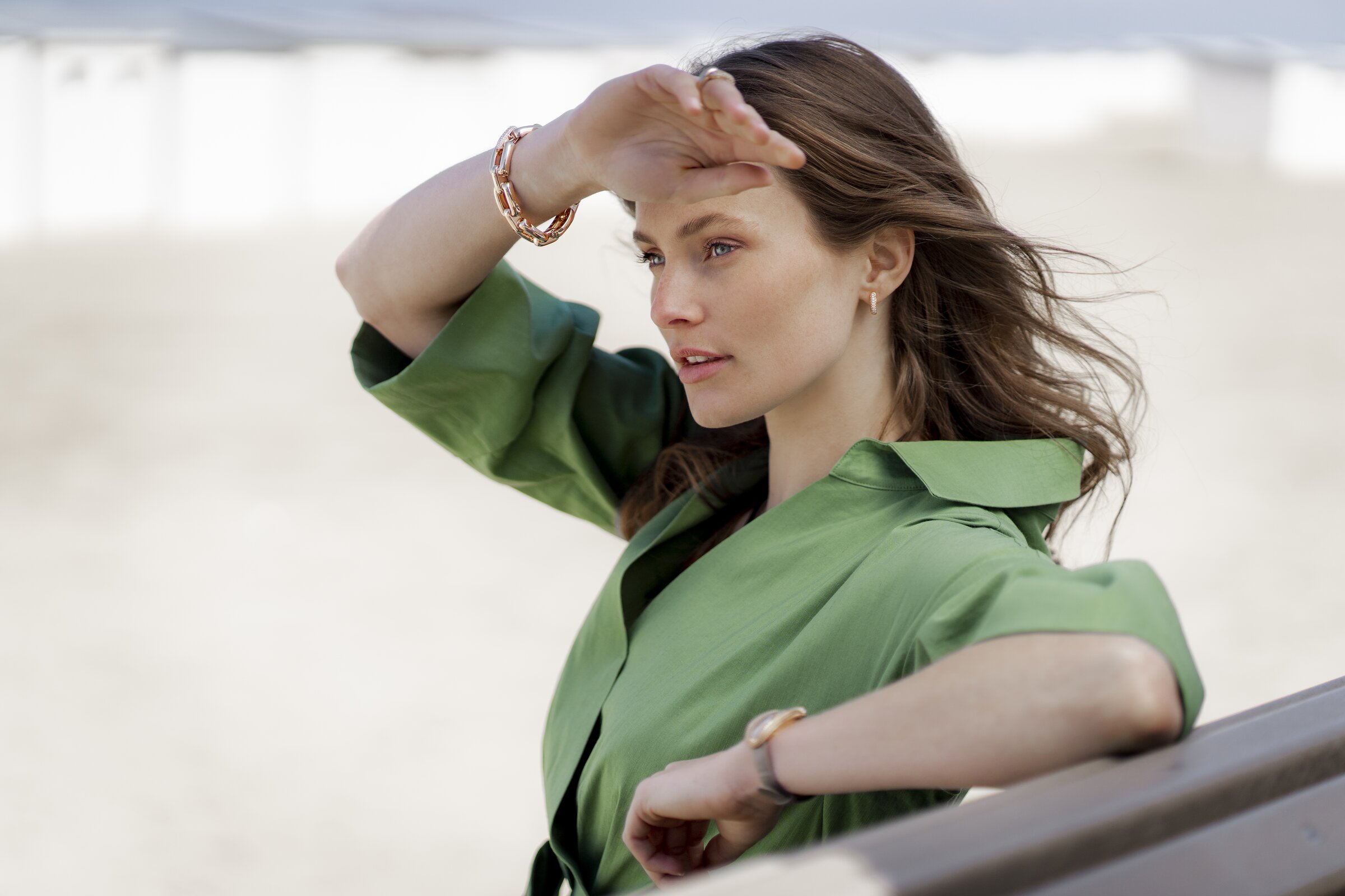 Model on the beach wearing Maison De Greef gold jewellery, bracelets and earrings